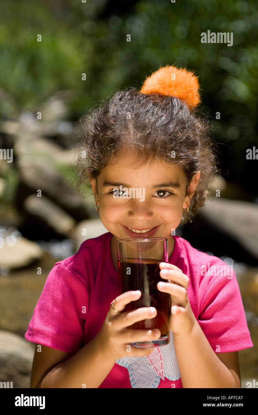 4 years old girl drinking mate at a picnic beside a brook Stock Photo