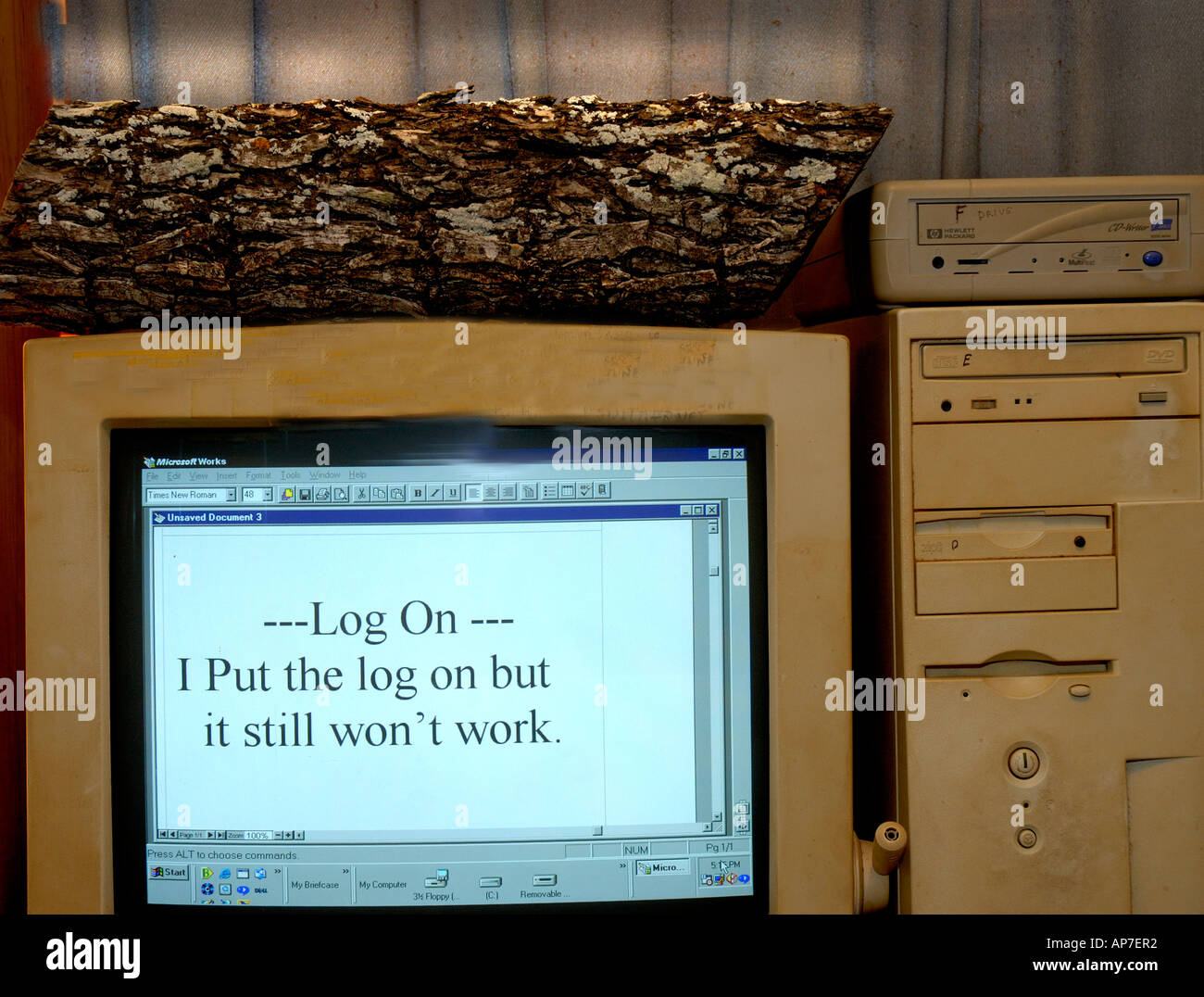 Log on top of computer. Computer humor humour. Copy on screen says I put the log on the computer still don'y work. Stock Photo