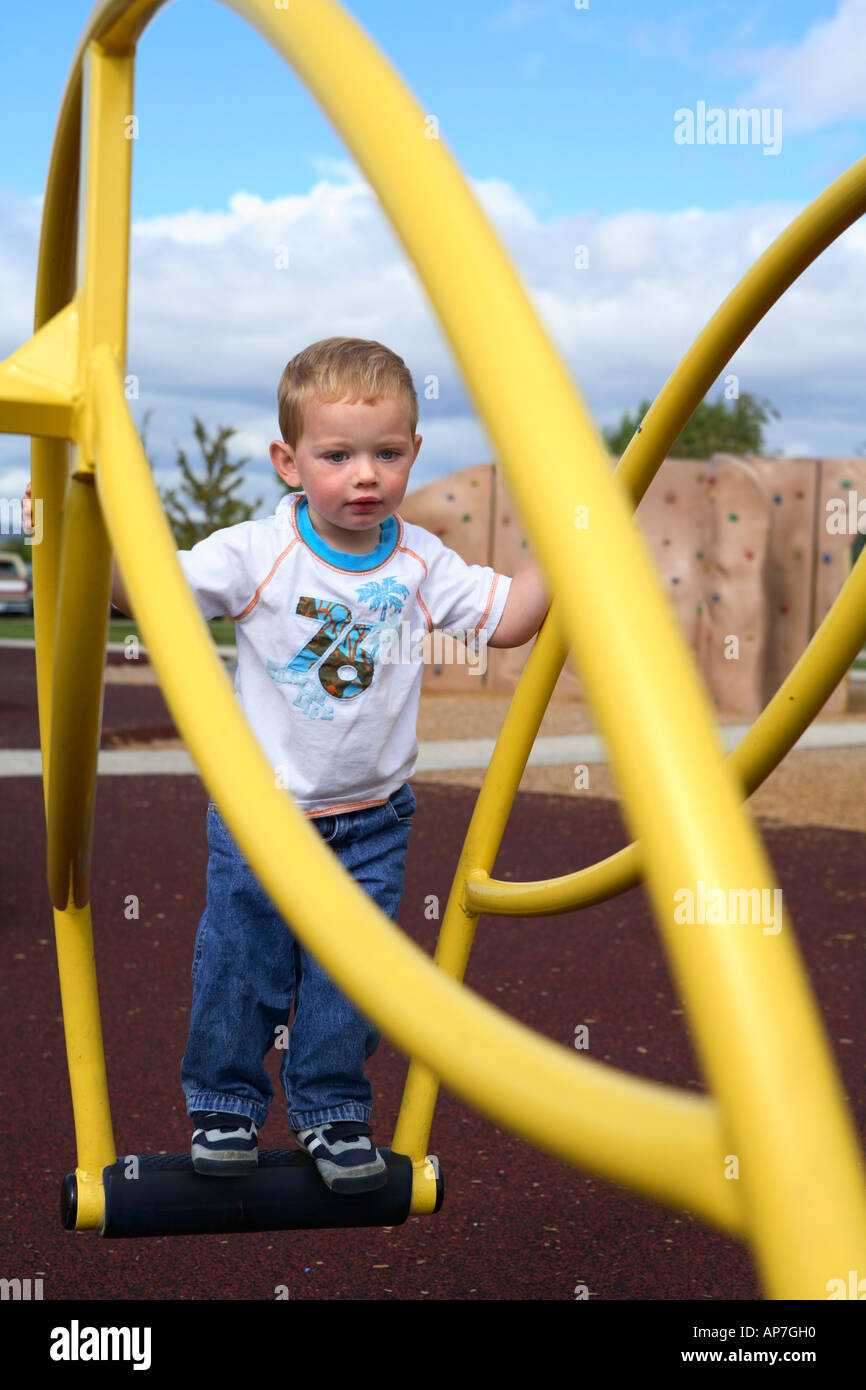 Two year old boy playing on park equipment Stock Photo
