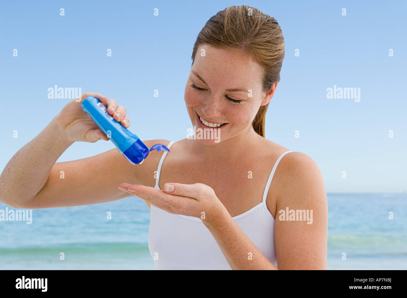 Young woman pouring suncream into hand Stock Photo