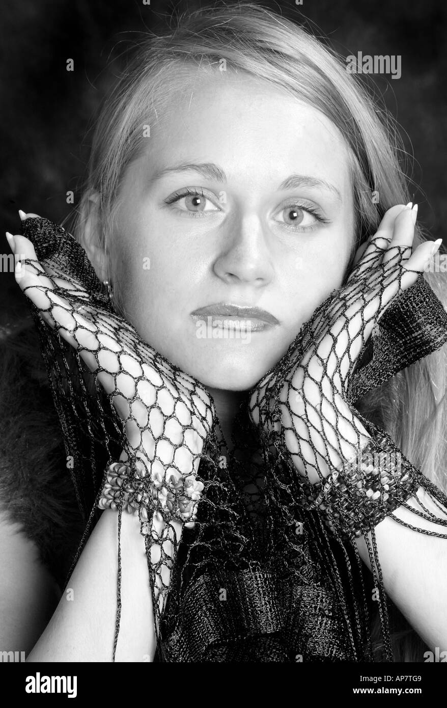 Portrait of a Young Girl With Long Blonde Hair Holding Her Face in Her Hands Stock Photo