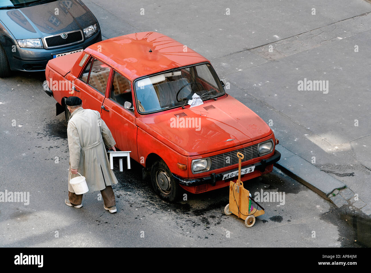 OLD MAN WASHING OLD EAST GERMAN CAR WARTBURG ON THE STREET Stock Photo