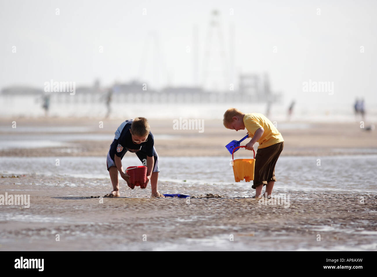 Two young boys playing on the beach with buckets and spades at