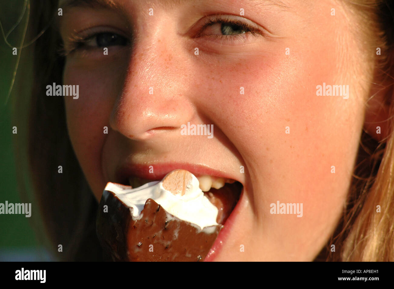 Portrait of young girl eating an ice cream lolly and looking happy Stock Photo
