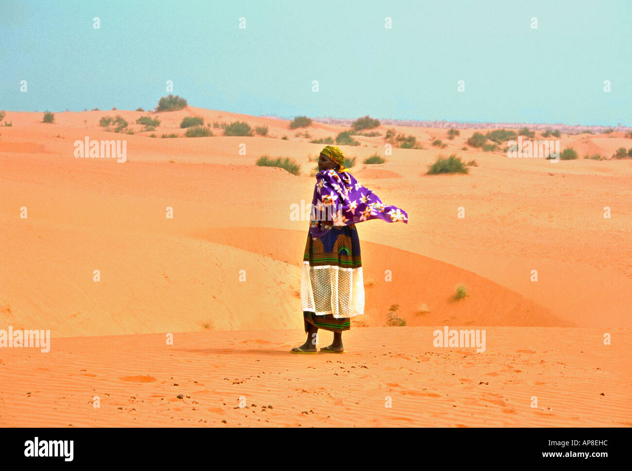 An african woman in traditional dress looking out over the sahara desert Stock Photo