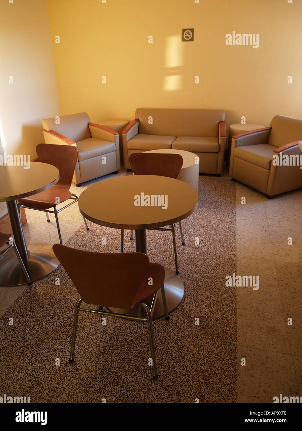 Interior of a lounge or waiting room with stuffed chairs and tables, naturally lit. Stock Photo