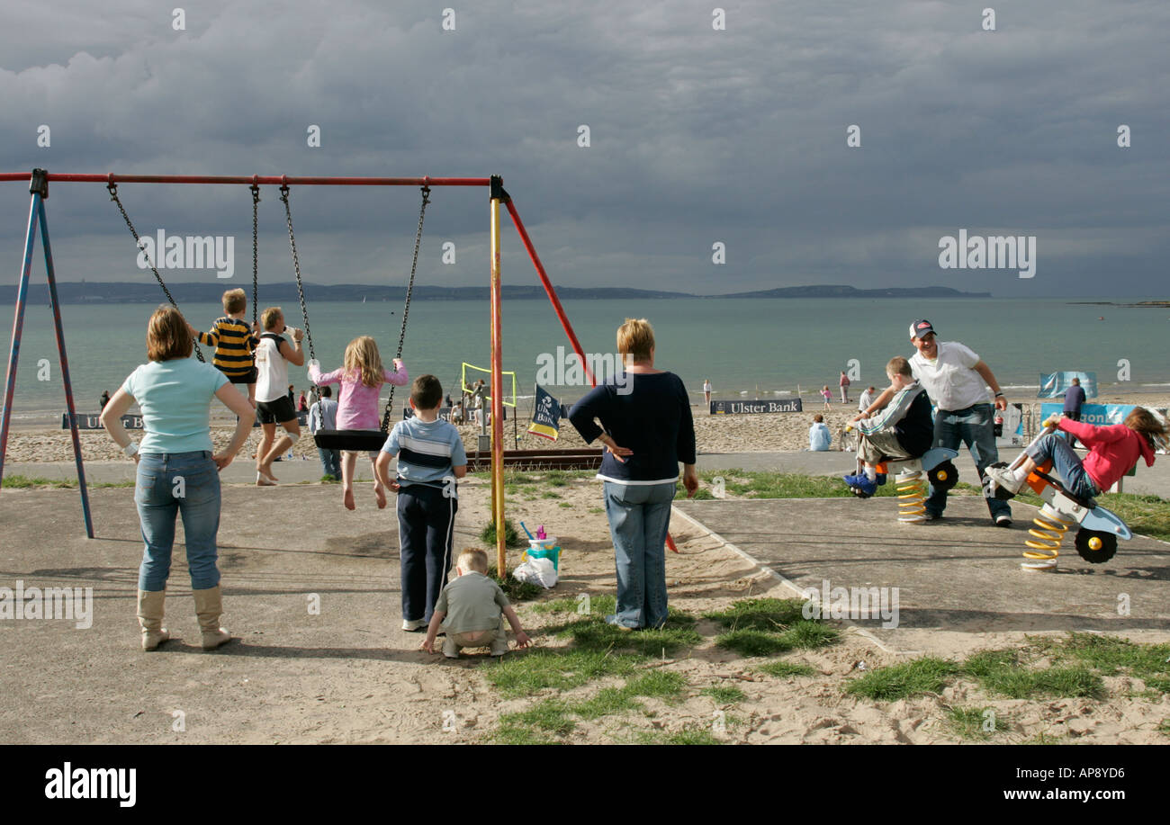 children and parents playing on swings and see saw at park at