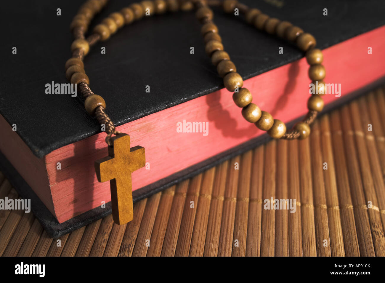 Closed  Bible with rosary beads on a straw mat /// crucifix cross Christianity Christian Catholic Wood wooden bead belief catholic Christ holy book Stock Photo