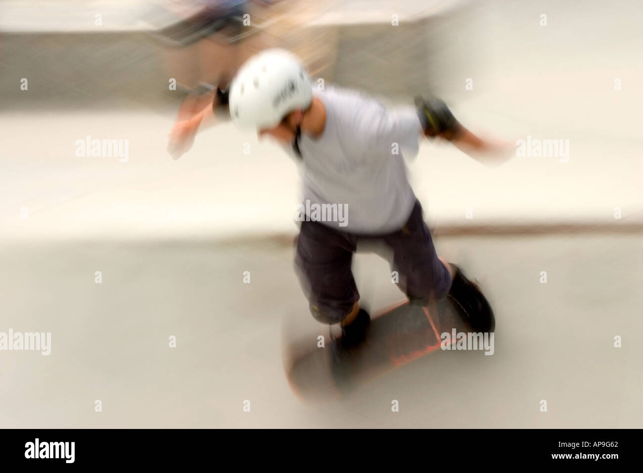 Dynamic motion blur image of a daring young man at a skateboard park. Stock Photo