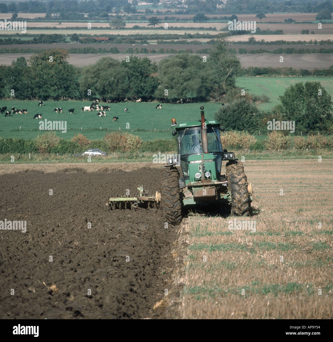 John Deere tractor ploughing stubble field on an organic farm Stock Photo