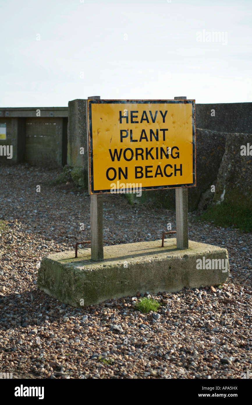 Yellow and black sign advising of heavy plant working on beach. Climping Beach, West Sussex, UK Stock Photo