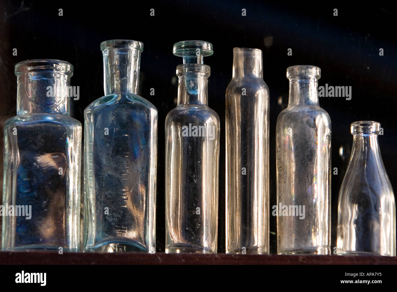 Old glass bottles on shelf against a dark background Stock Photo