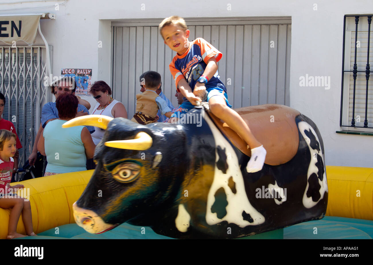 Young boy riding bucking mechanical bull, Mijas Pueblo, Andalucia, Costa del Sol, Spain Stock Photo