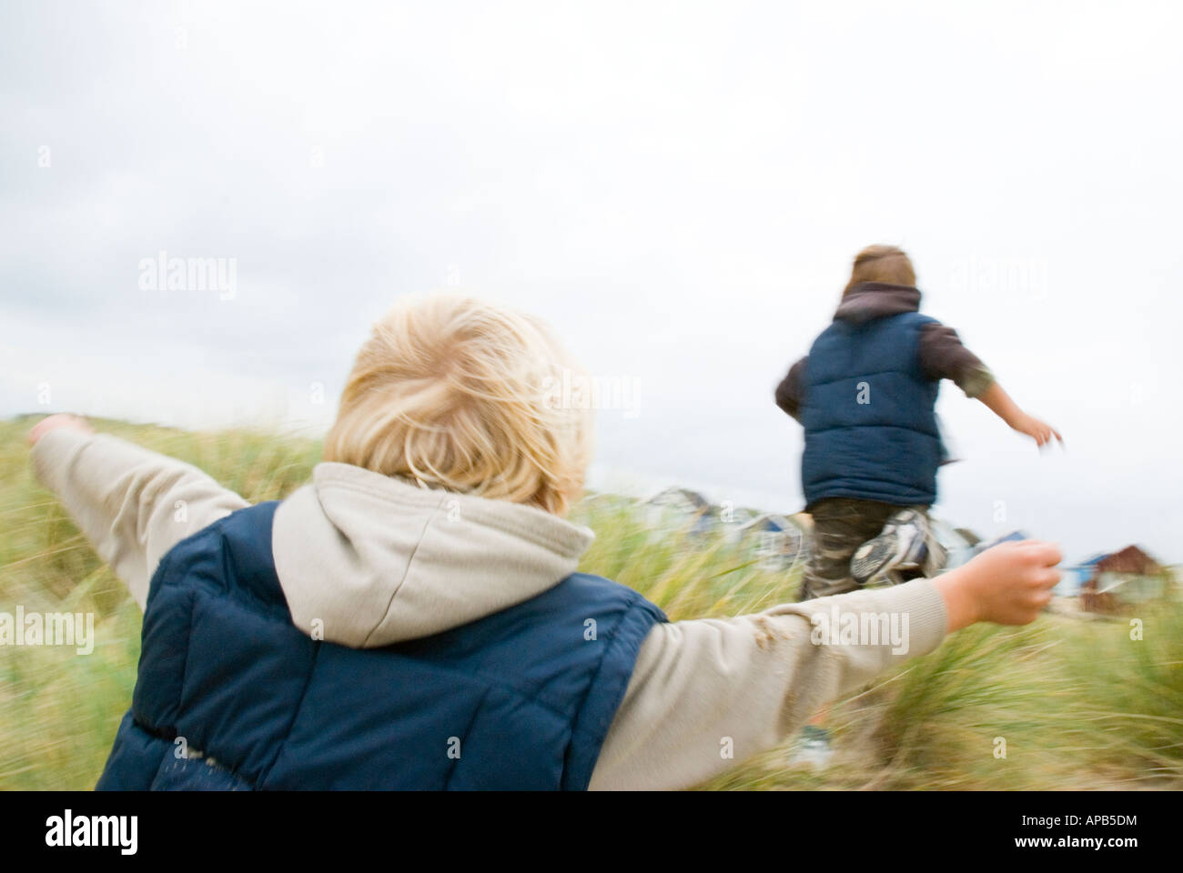 Two young brothers chasing each other on a beach in Bournemouth,Dorset,England. Stock Photo