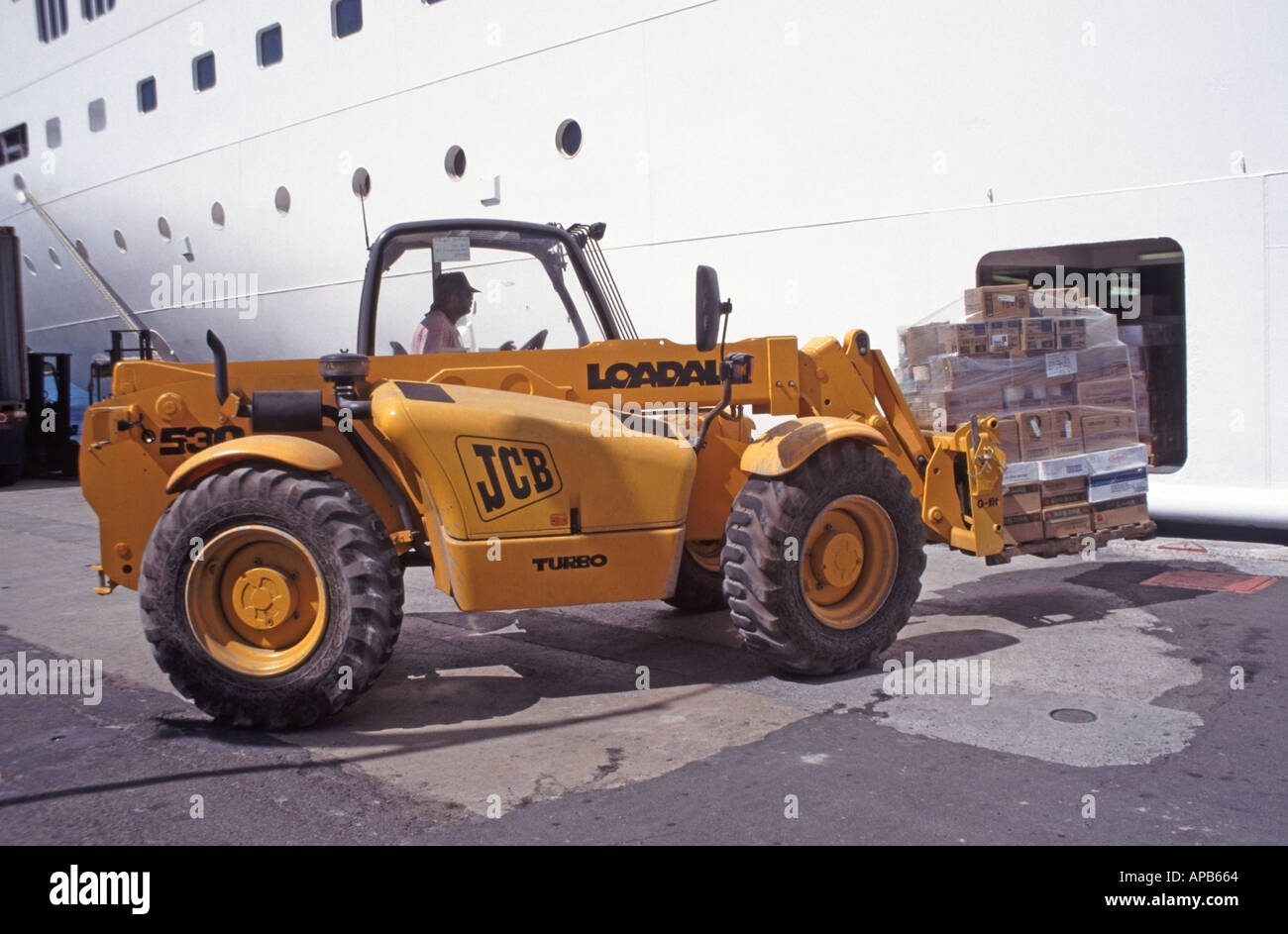 Cruise ship liner at Charlotte Amalie port in St Thomas in US Virgin Islands Caribbean hold loaded with provisions by JCB fork lift truck and driver Stock Photo