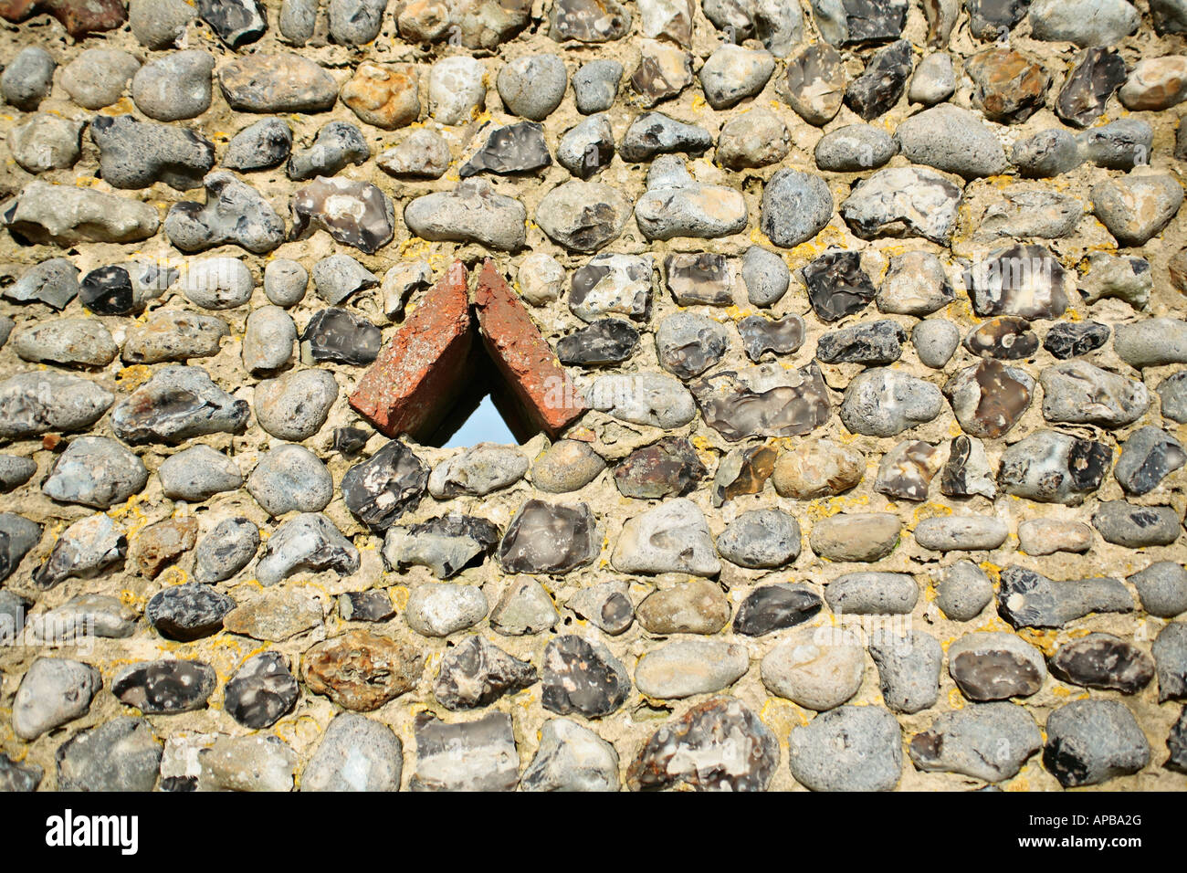 Small triangular opening in a traditional Sussex flint wall Stock Photo