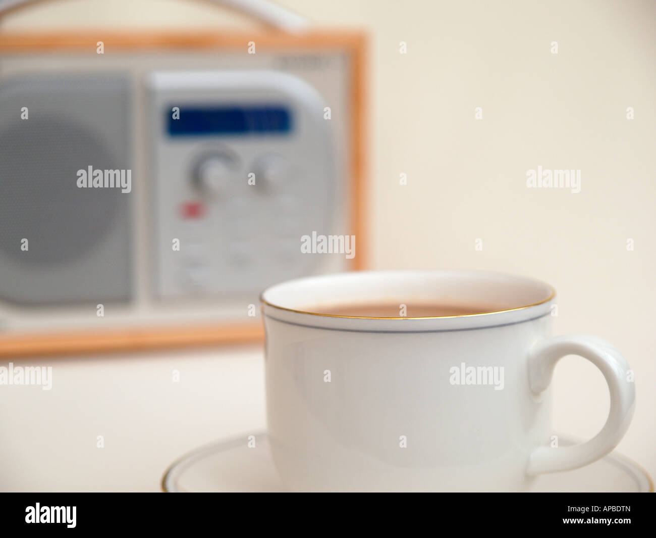 WHITE CHINA COFFEE CUP and SAUCER with a digital radio in the background Stock Photo
