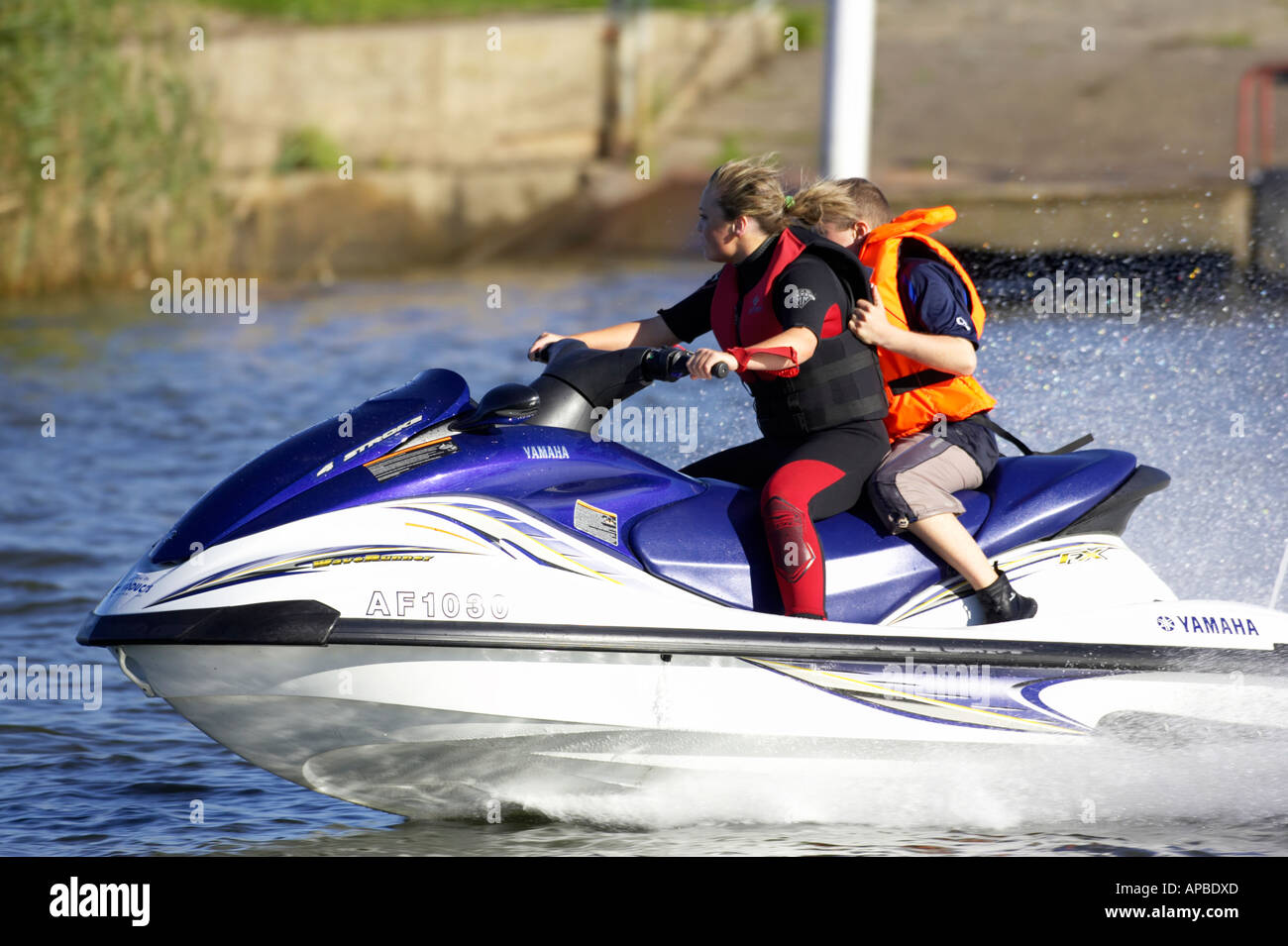 young woman in wetsuit driving a yamaha 4 stroke AF1030 waverider with  young boy passenger at speed Stock Photo - Alamy