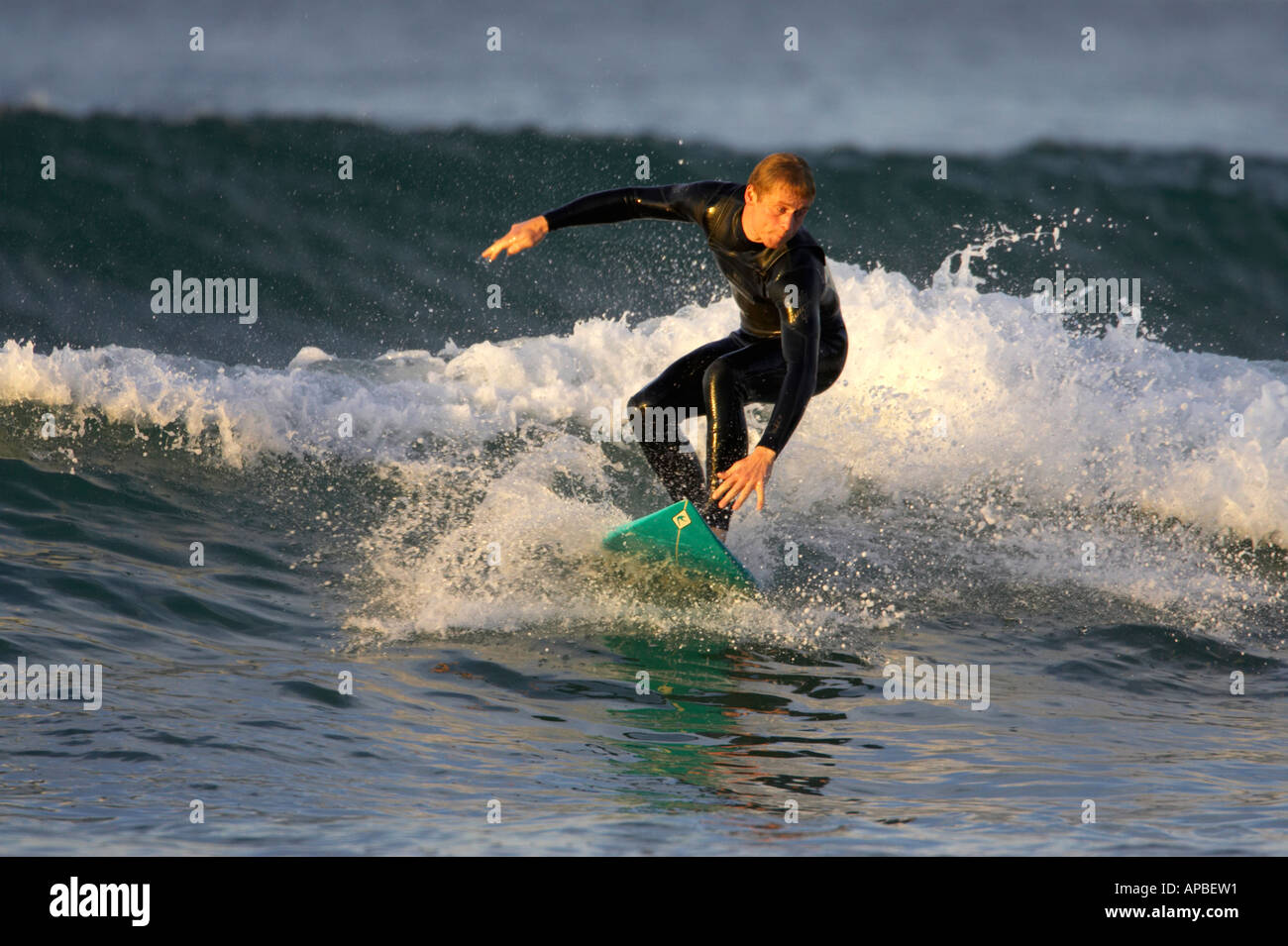 male surfer in wetsuit surfs on waves off white rocks beach portrush