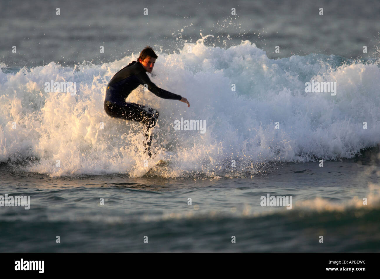 male surfer in wetsuit surfs on waves off white rocks beach portrush
