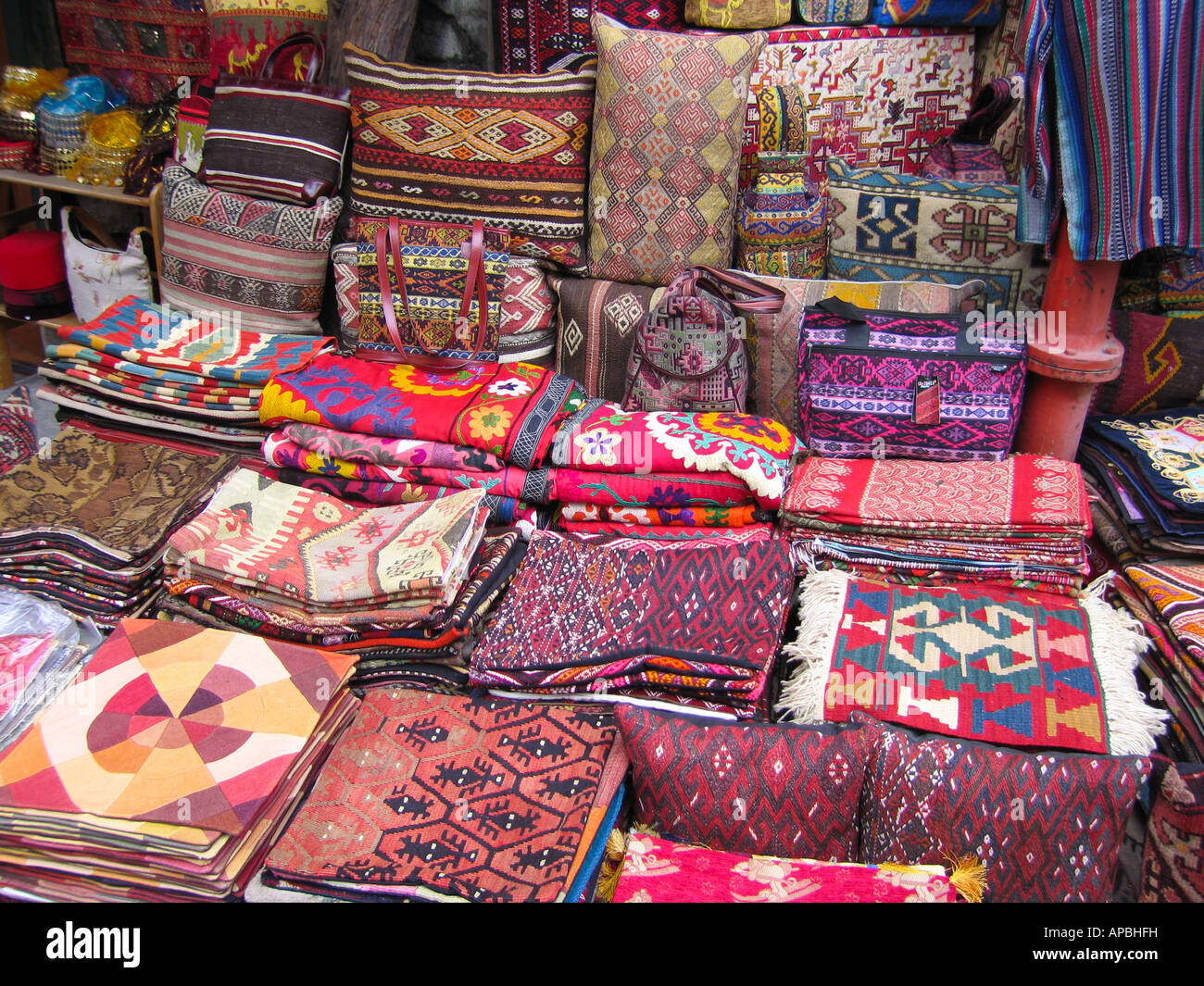 Piles of mats and cushions, bags on a market stall selling traditional Turkish patterned fabrics Stock Photo