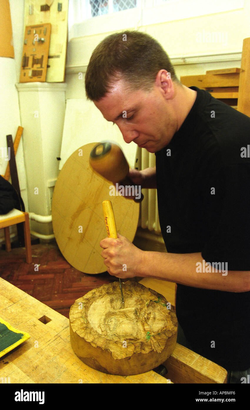 Man using mallet and chisel in construction of a wooden ornament in ...