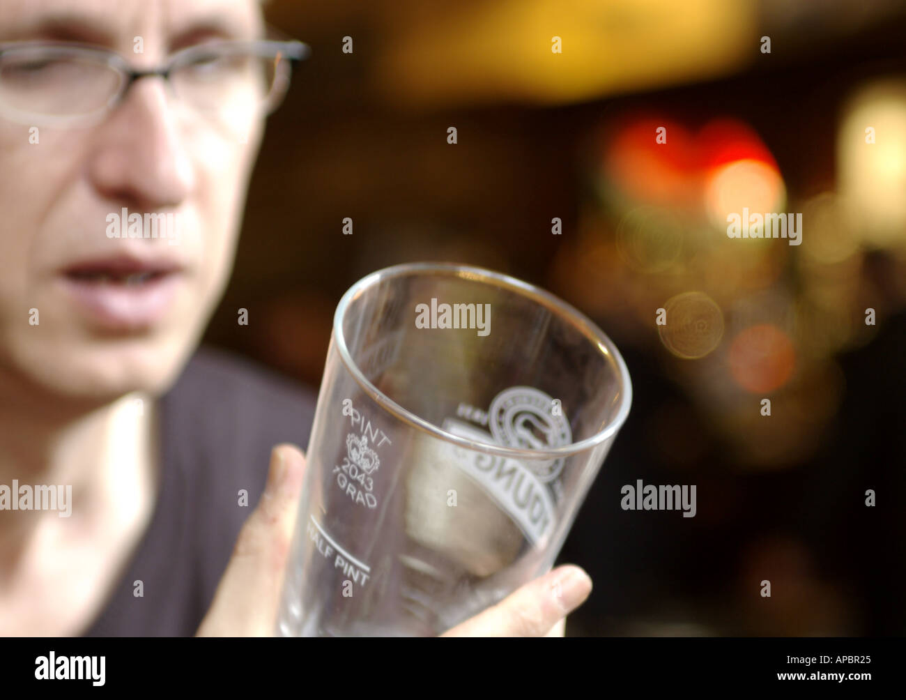 Man looking baffled at empty Youngs beer glass Stock Photo
