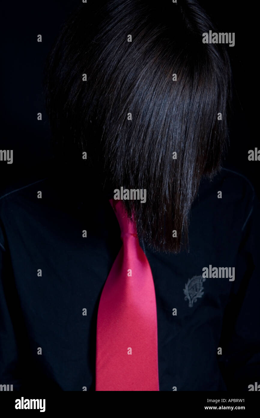 Fashion pop style image of a young male with shiny hair and long fringe in pink tie and black shirt Stock Photo