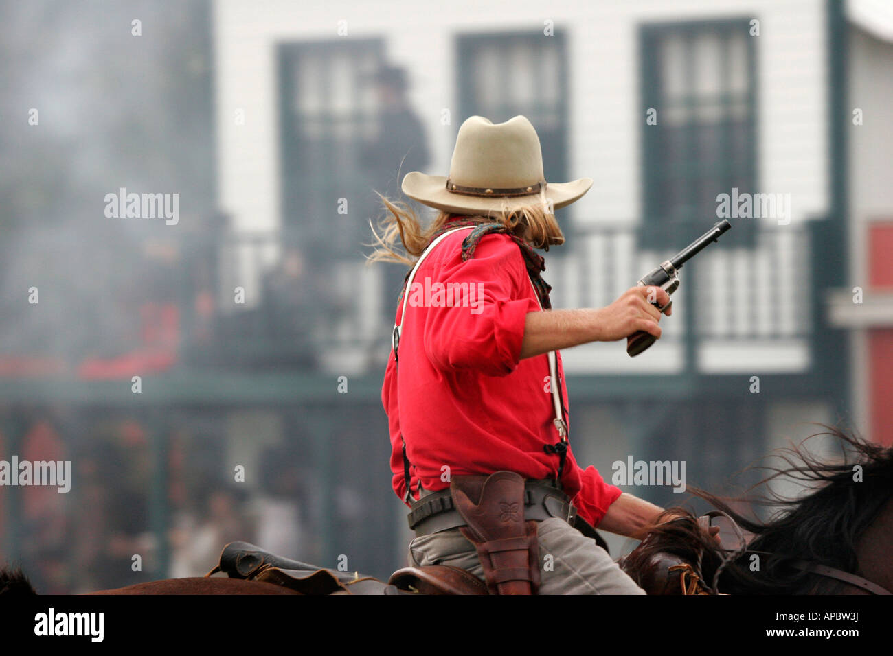 A armed cowboy with a gun riding horseback in a shootout with the towns people at a 1850s western reenactment Stock Photo