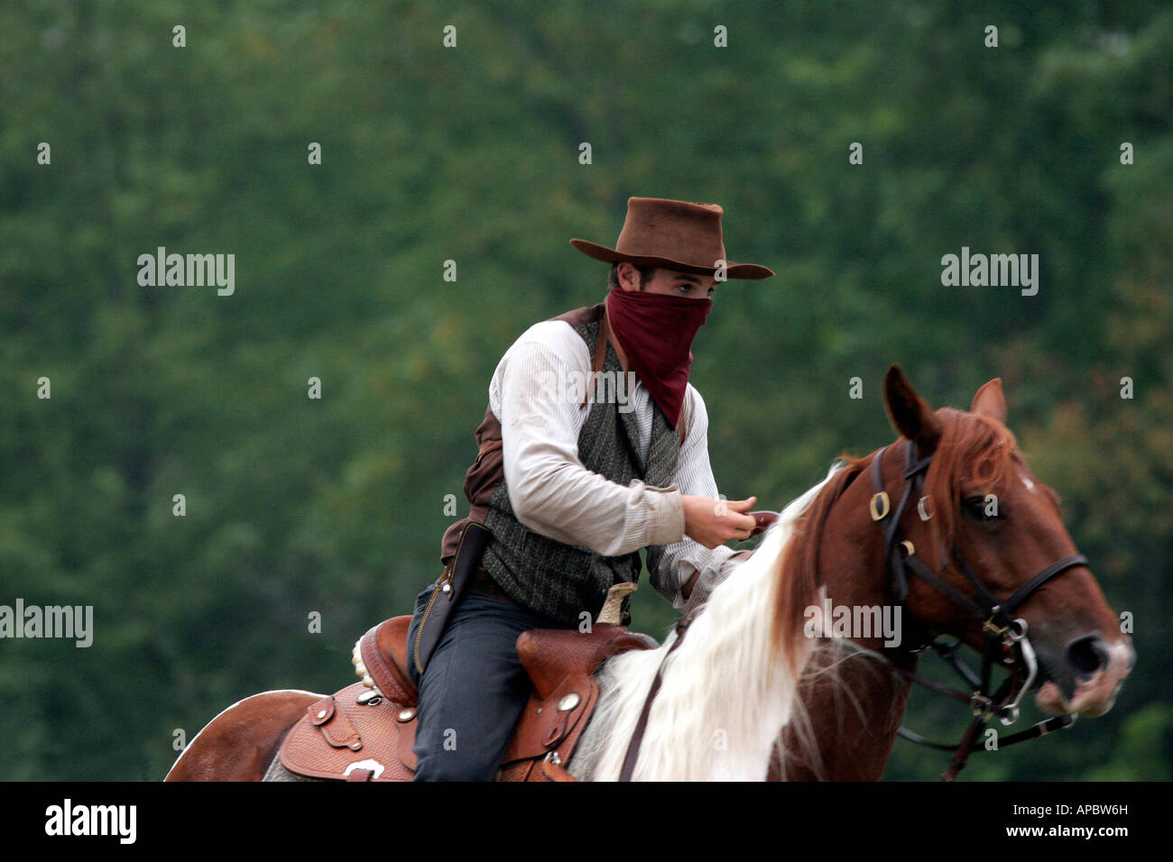 A young male cowboy bandit riding horseback Stock Photo