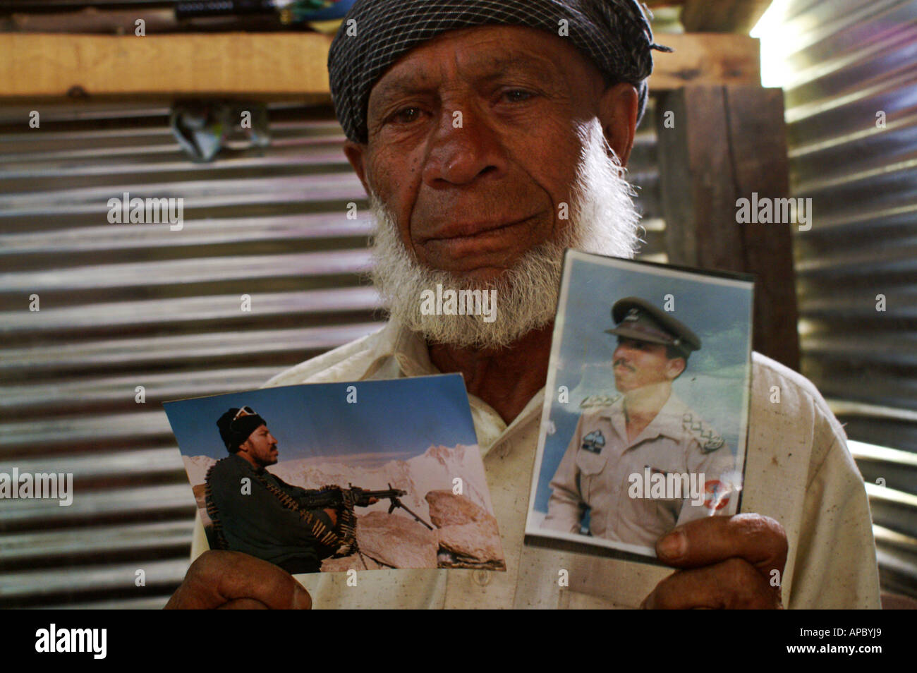 Old man in a shelter holding photographs of his son who died in the earthquake, Sarash Village, Manshera, NWFP, Pakistan Stock Photo
