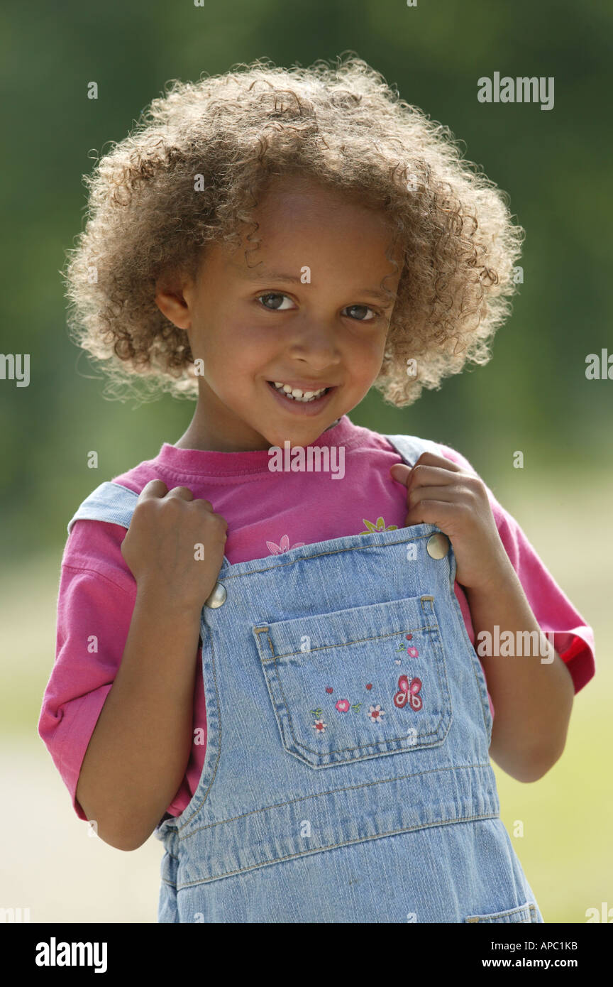 Portrait of young girl wearing dungarees Stock Photo - Alamy
