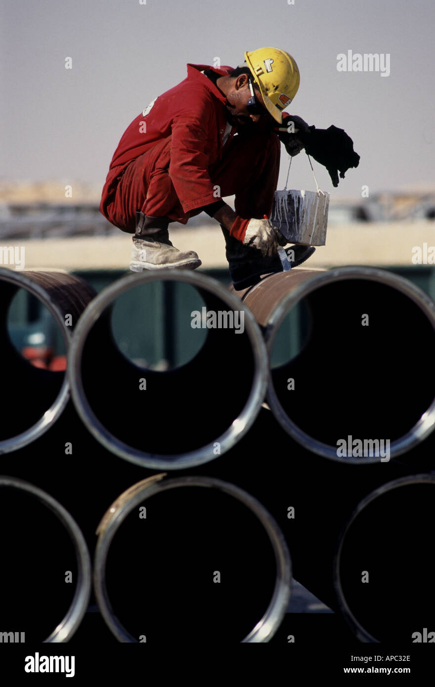 Maintenance worker painting pipes used on oil rig in Harad Saudi Arabia Stock Photo