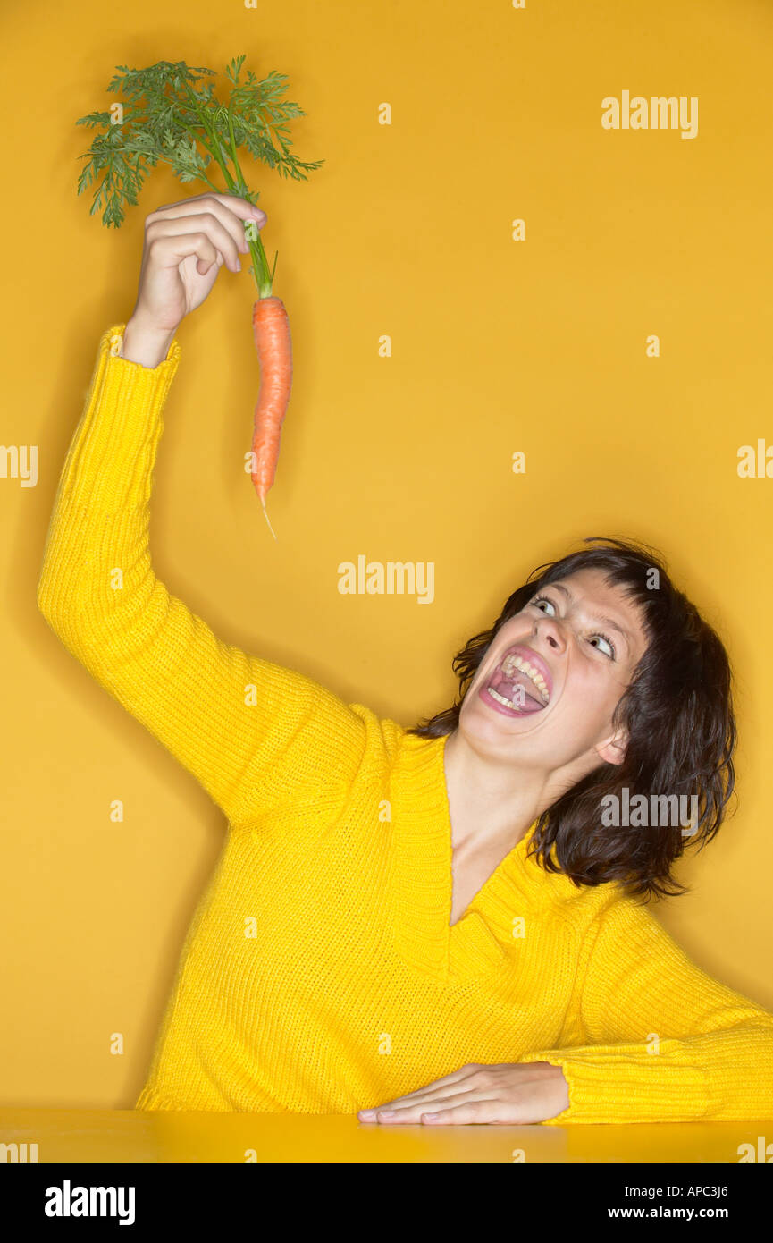 Woman upholding a raw carrot Stock Photo