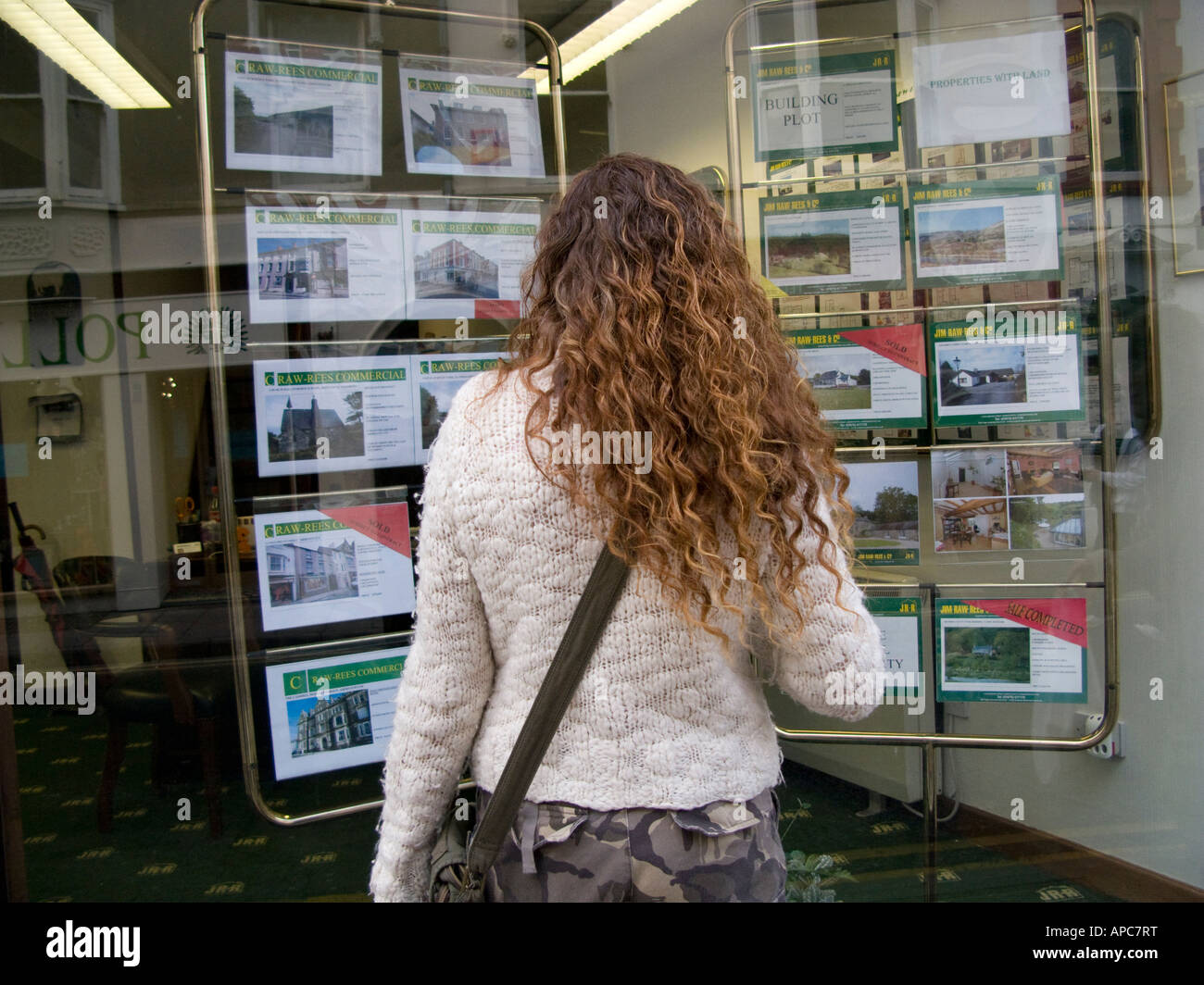 rear view of young single woman with long hair looking at house price