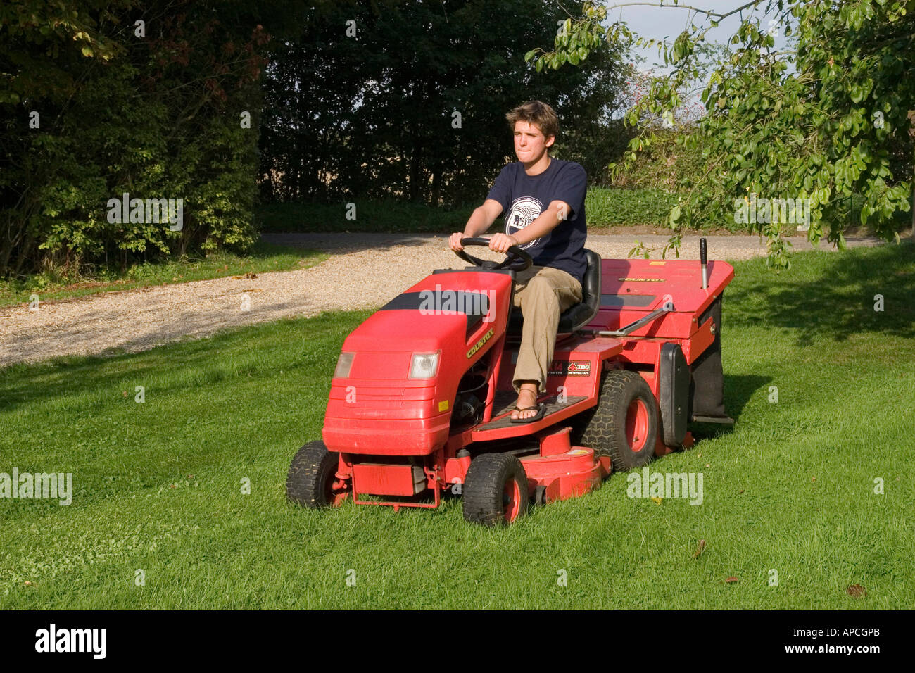 Using a ride on petrol driven tractor mower to cut garden lawn with