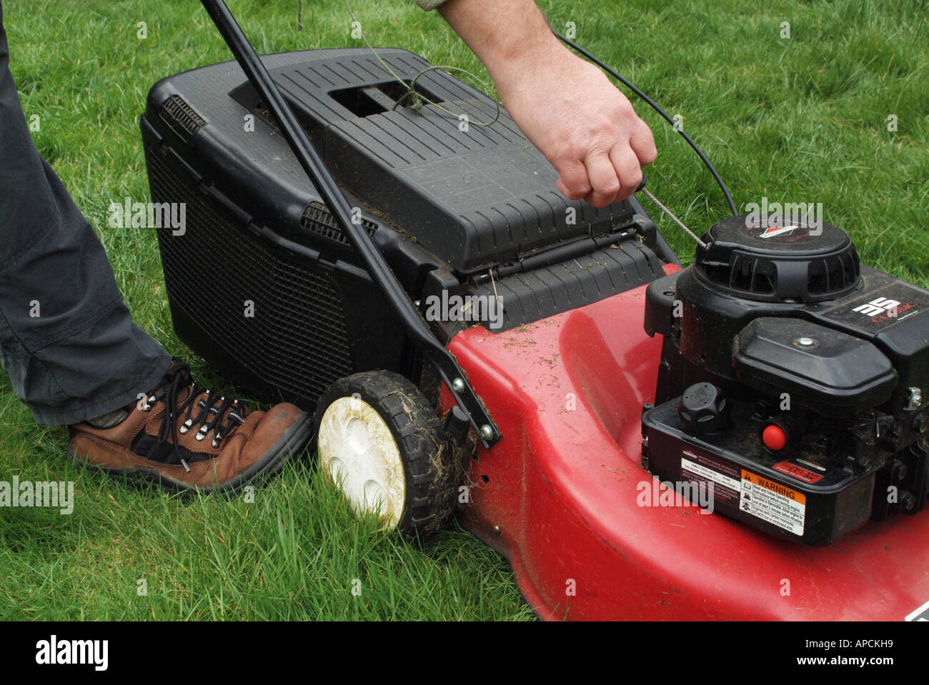 Starting the engine of a petrol driven lawn mower Stock Photo