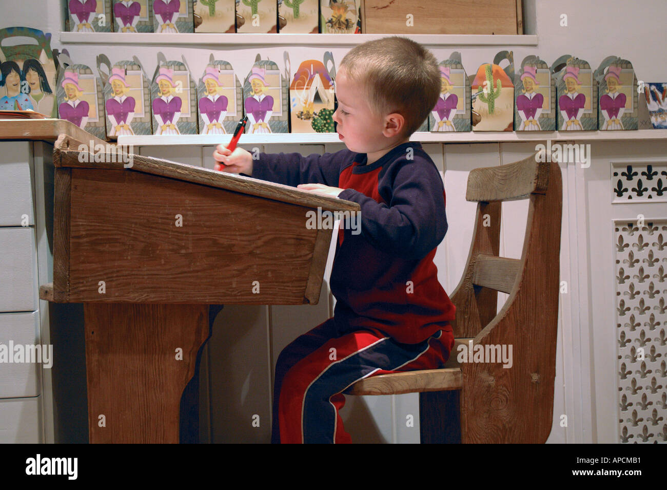 Young 4 Year Old Boy Sitting At Victorian School Desk Drawing And