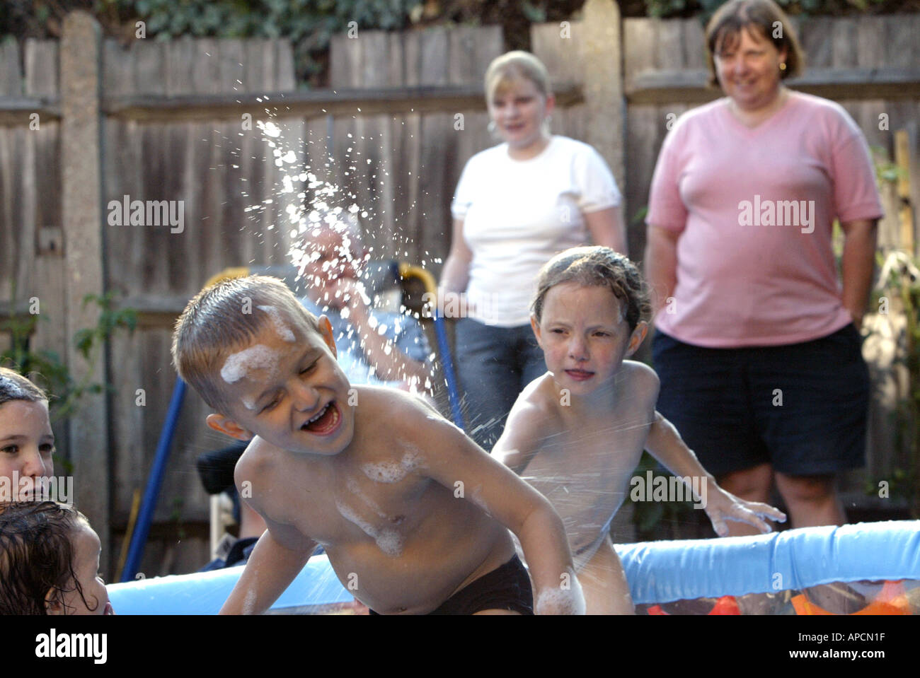 High spirited family play in garden paddling pool Stock Photo