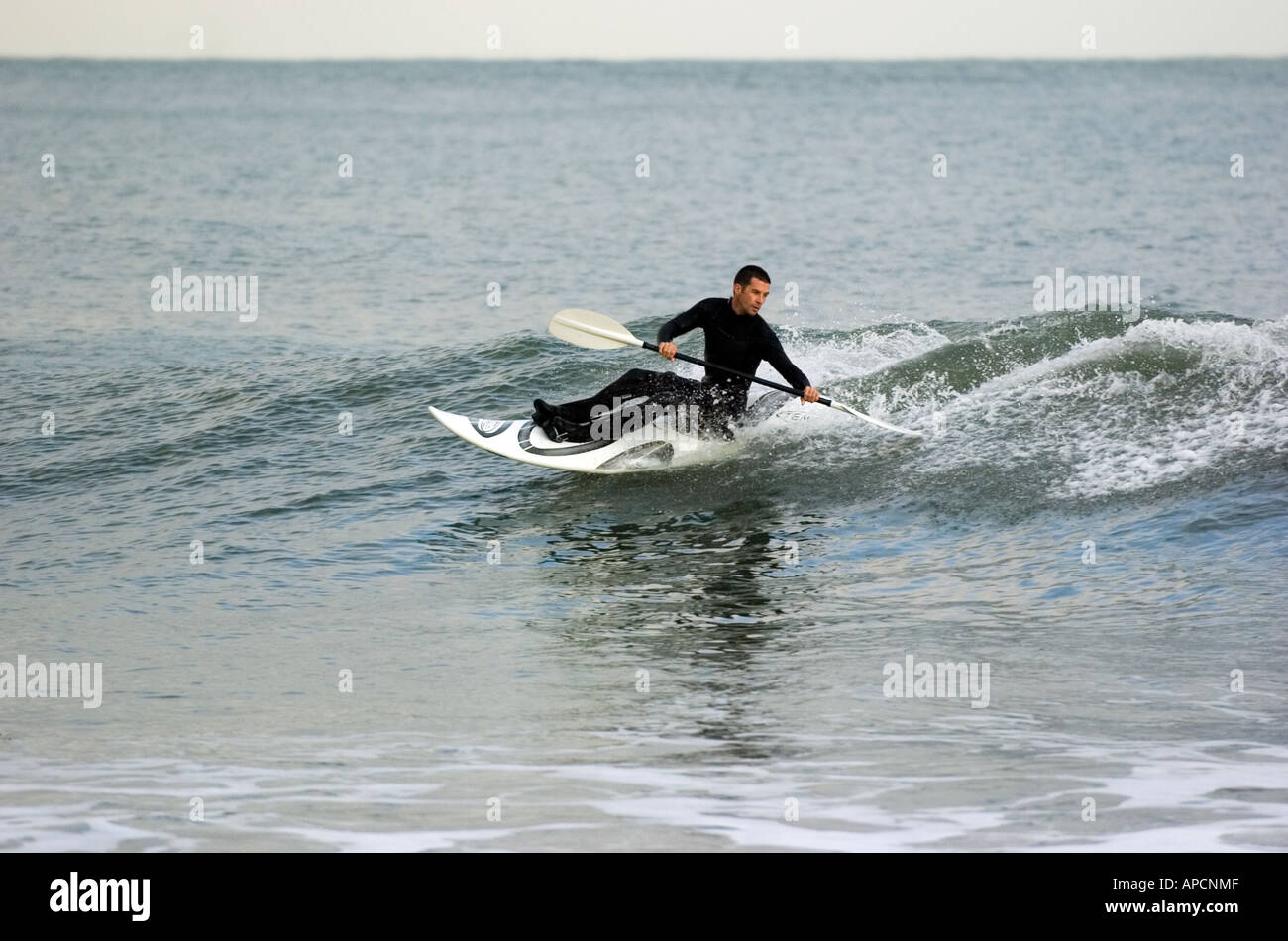 Surf skier riding the surf in Bracelet Bay,Limeslade near Swansea alongside the Mumbles lighthouse. Stock Photo