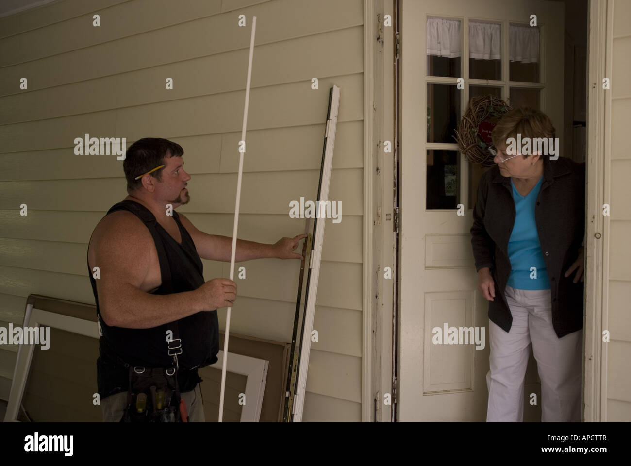 Woman talking to handyman about to install new doors on her house Stock Photo