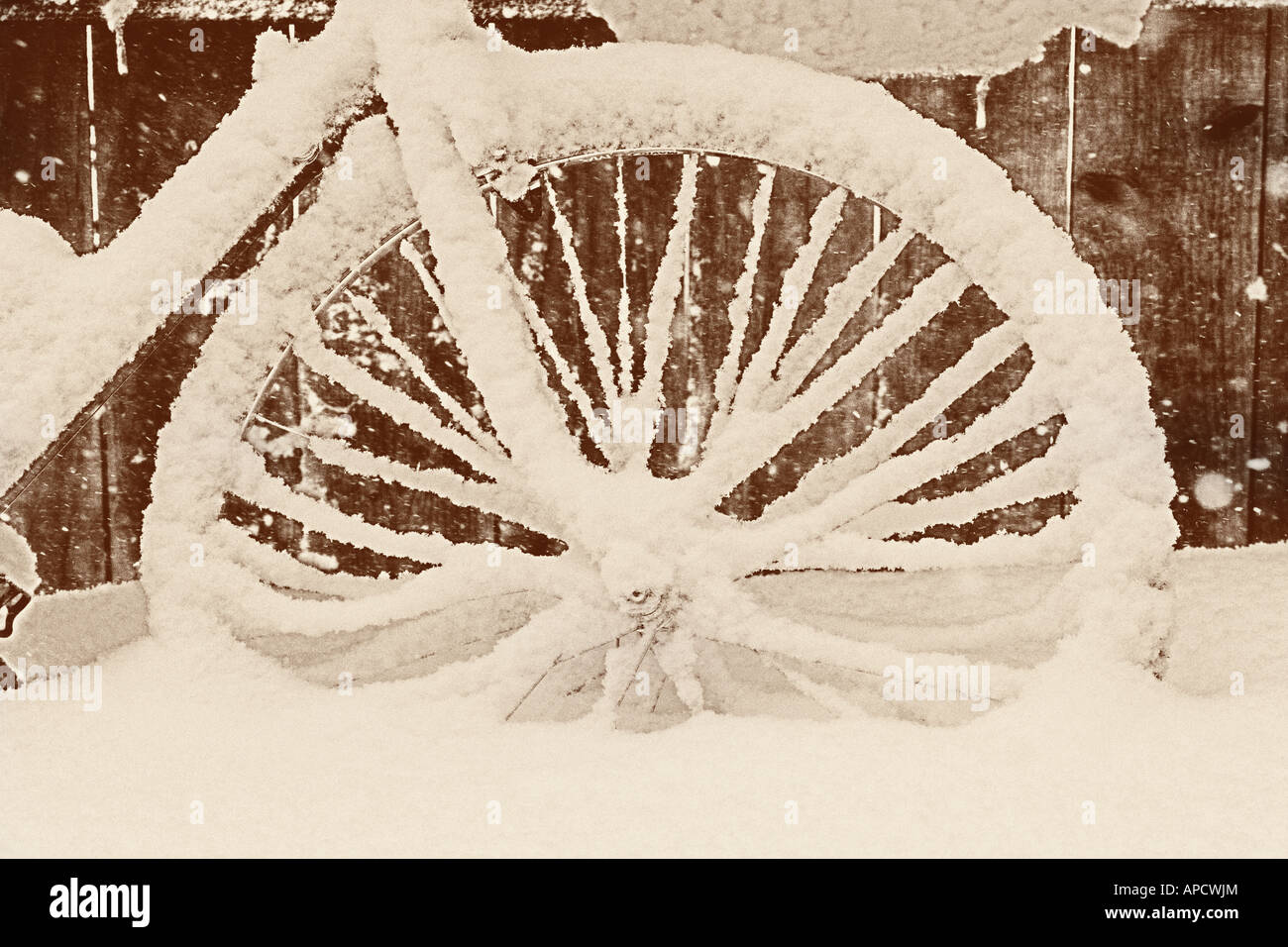 A bicycle covered with snow next to a fence. Stock Photo