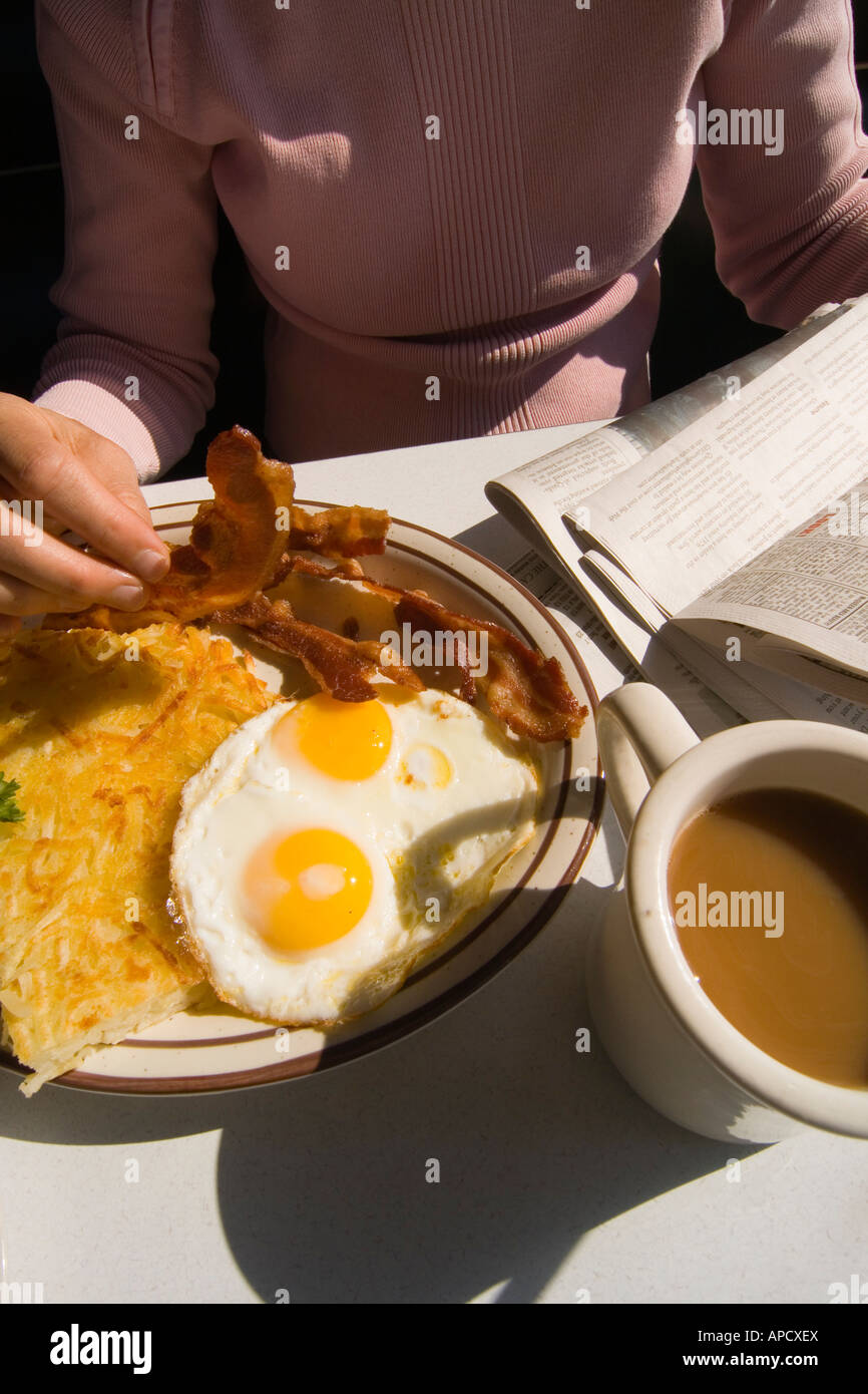 A woman eating breakfast and reading a newspaper in a diner in Truckee