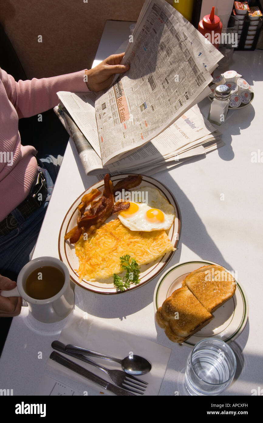 A woman eating breakfast and reading a newspaper in a diner in Truckee