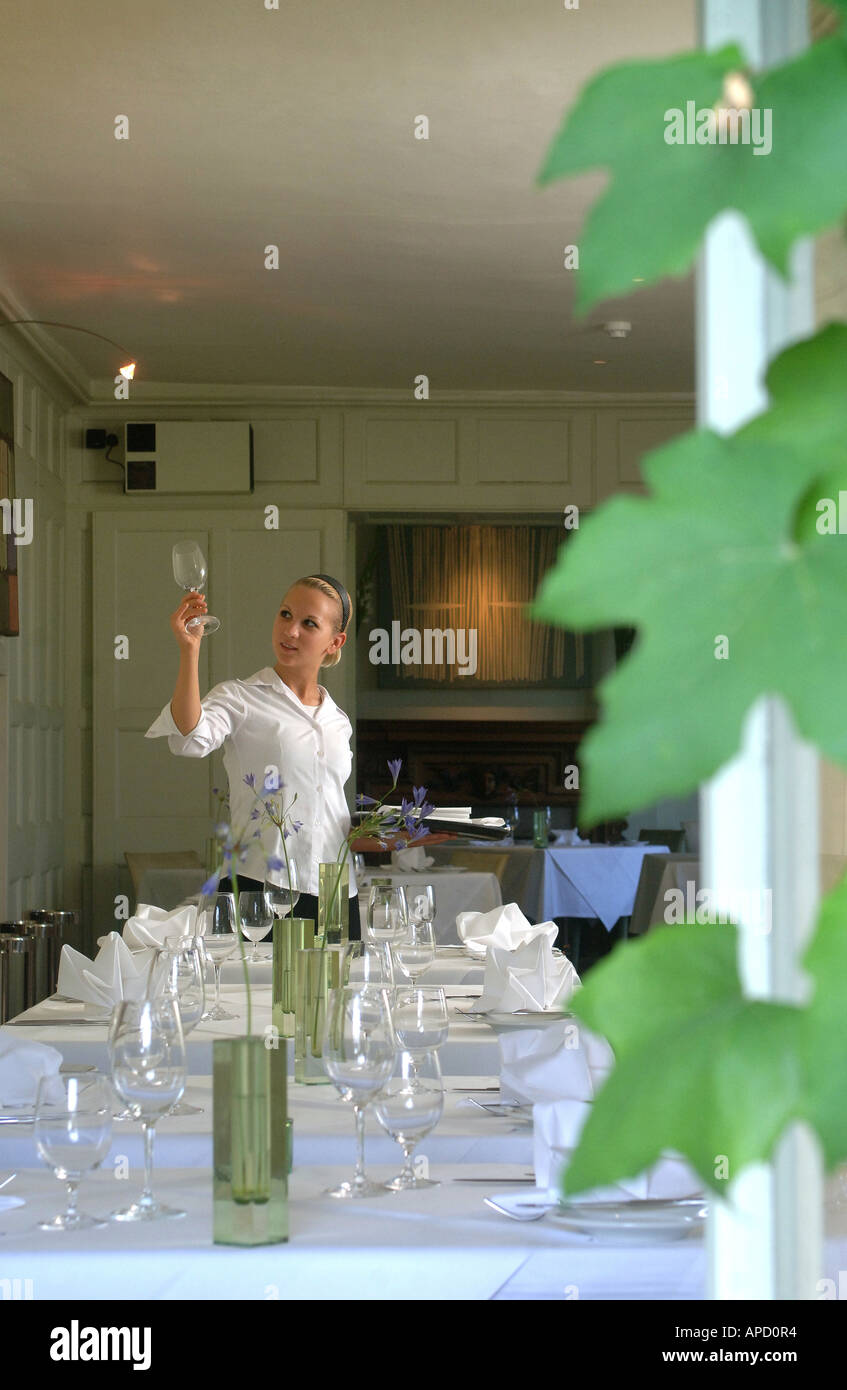 A waitress checking glasses at a restaurant table silver service Barnsley House Restaurant Barnsley near Cirencester Stock Photo