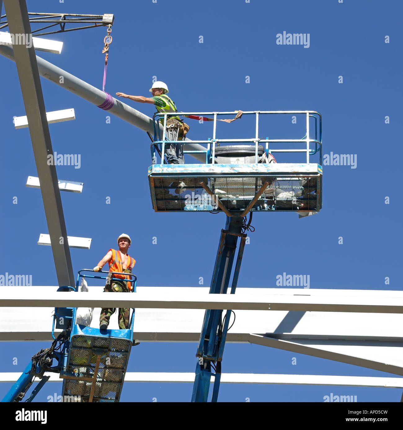 Steel erectors on two cherry pickers access platform during