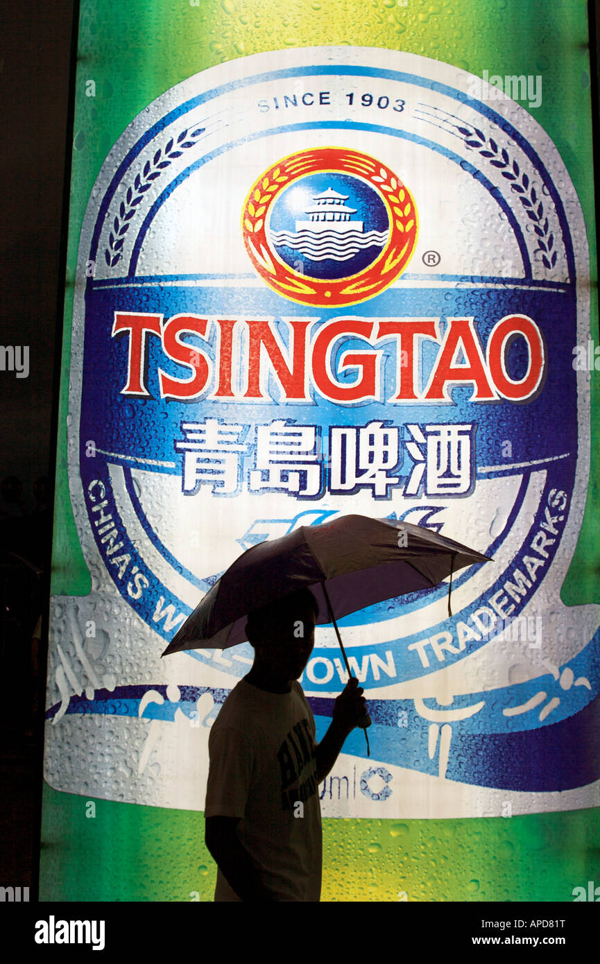 A man walks past an illuminated Tsingtao beer sign at the Tsingtao International beer festival Qingdao Shandong China Stock Photo