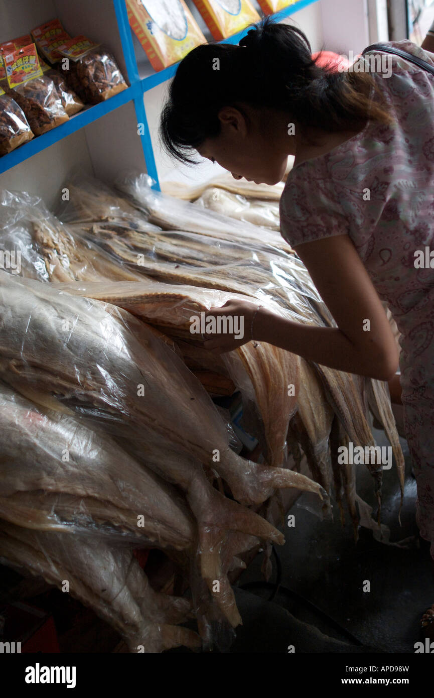 A woman looks at a fillet of salted fish in a food store Qingdao Shandong China Stock Photo