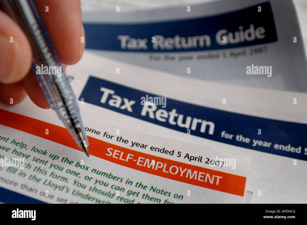 A hand seen filling in the Tax Return form using the tax return guide