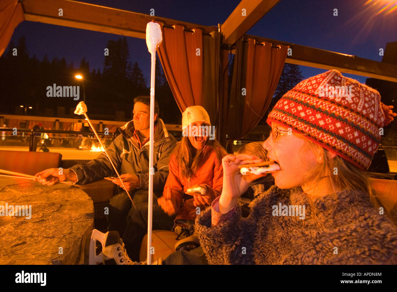 A young girl eating smores with her family by an ice skating rink at Northstar ski resort near Lake Tahoe in California Stock Photo